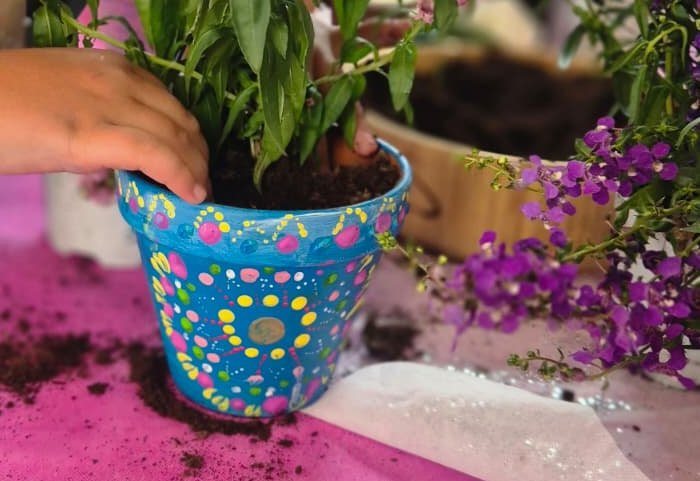 An art and planting workshop at a girls' birthday party at Moba Center — a mandala-painted pot